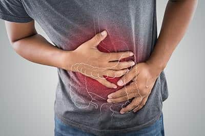 man holding hands over stomach with red light