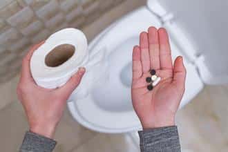 Woman holding pill and toilet paper roll