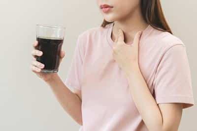 woman holding glass of dark liquid